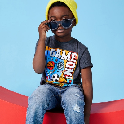 A child wearing the Play All Day tee shirt, a knit cap and sunglasses 