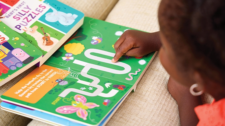 A child tracing a maze path in one of Highlights’ baby books.