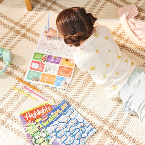 A child writing inside a puzzle book.